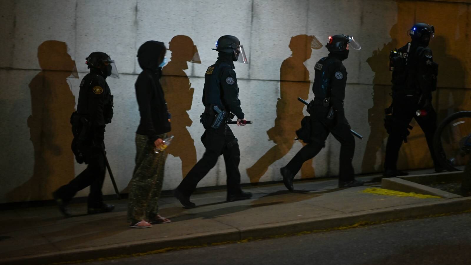 A bystander watches Portland police officers depart.