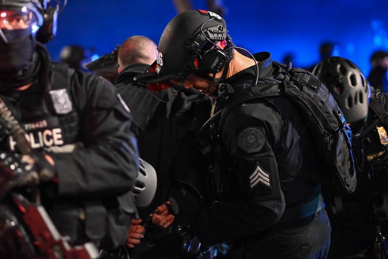 Rapid Response team officers handcuff a person in downtown Portland