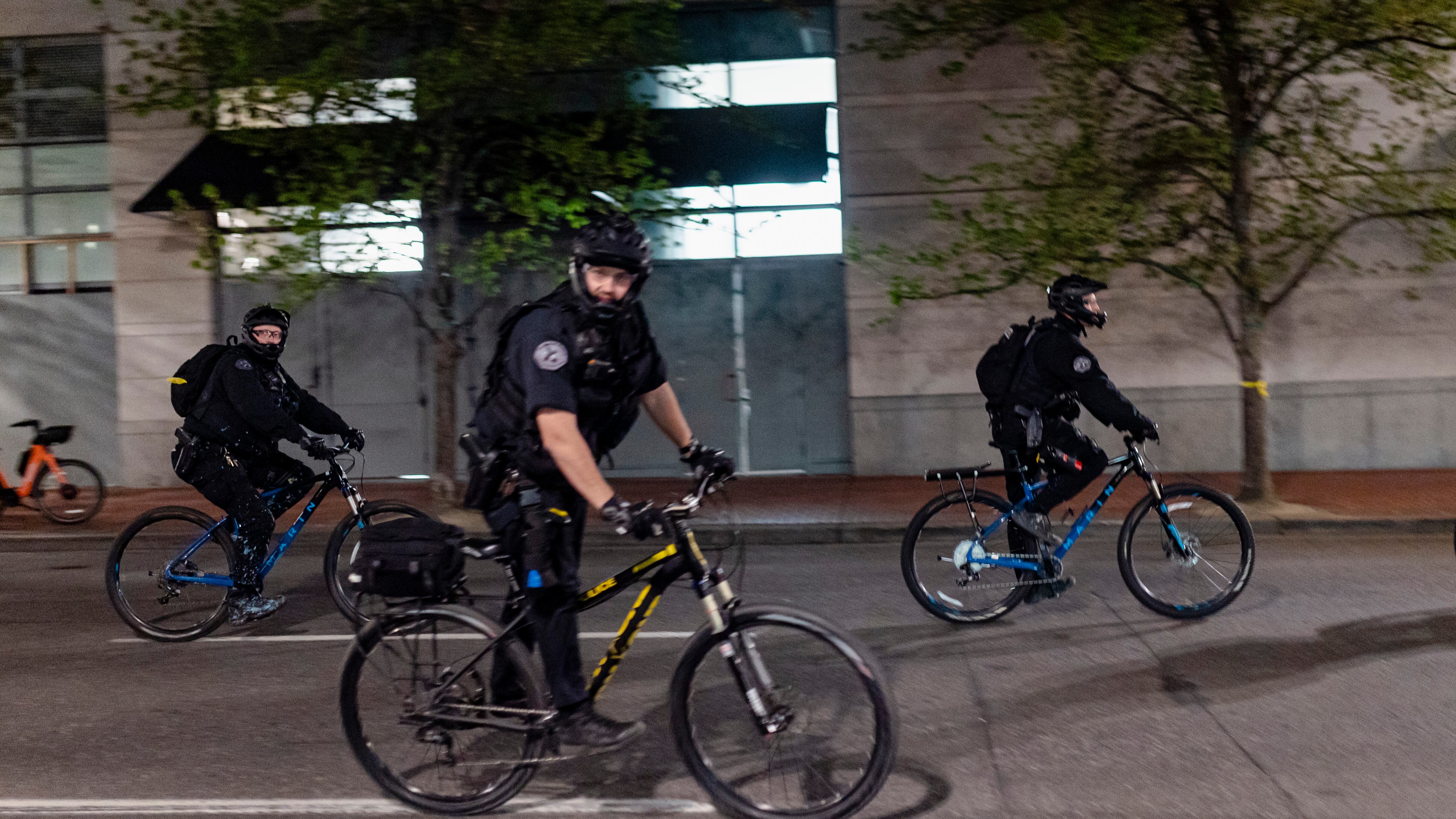 Portland police officers patrol a downtown protest by bicycle.