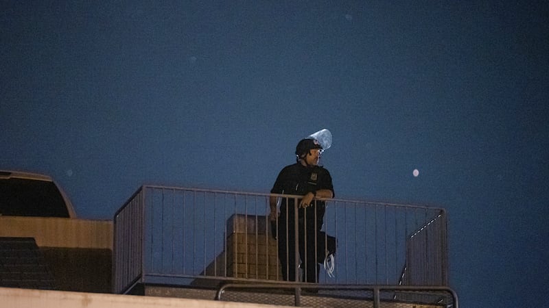 A Portland police officer observes an April 17 protest from the roof of the East Precinct parking garage.