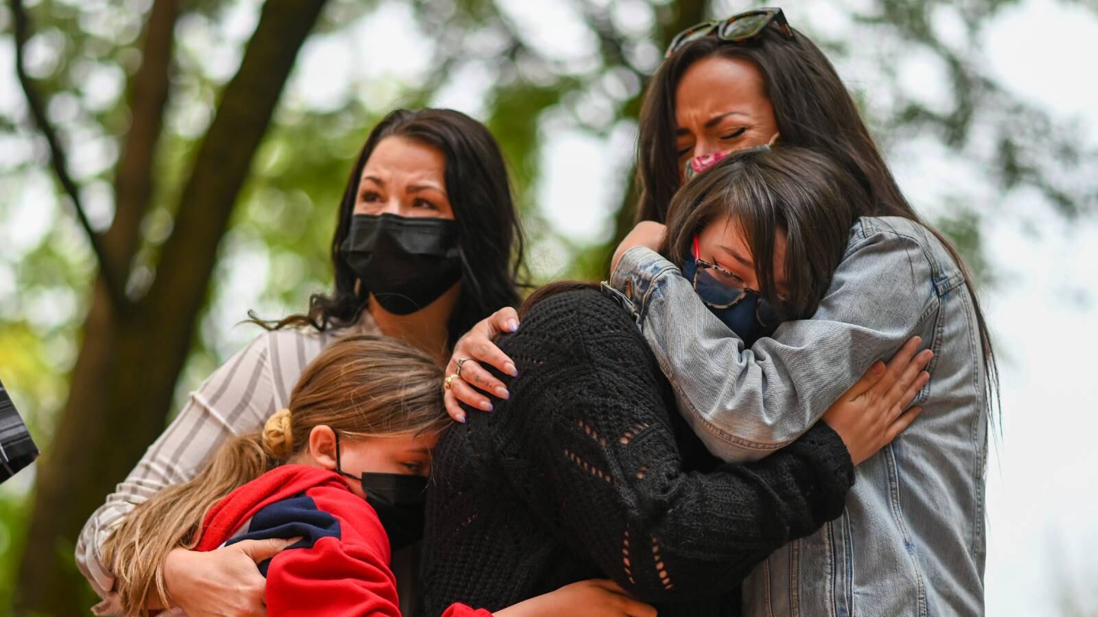 Family members hug and cry.