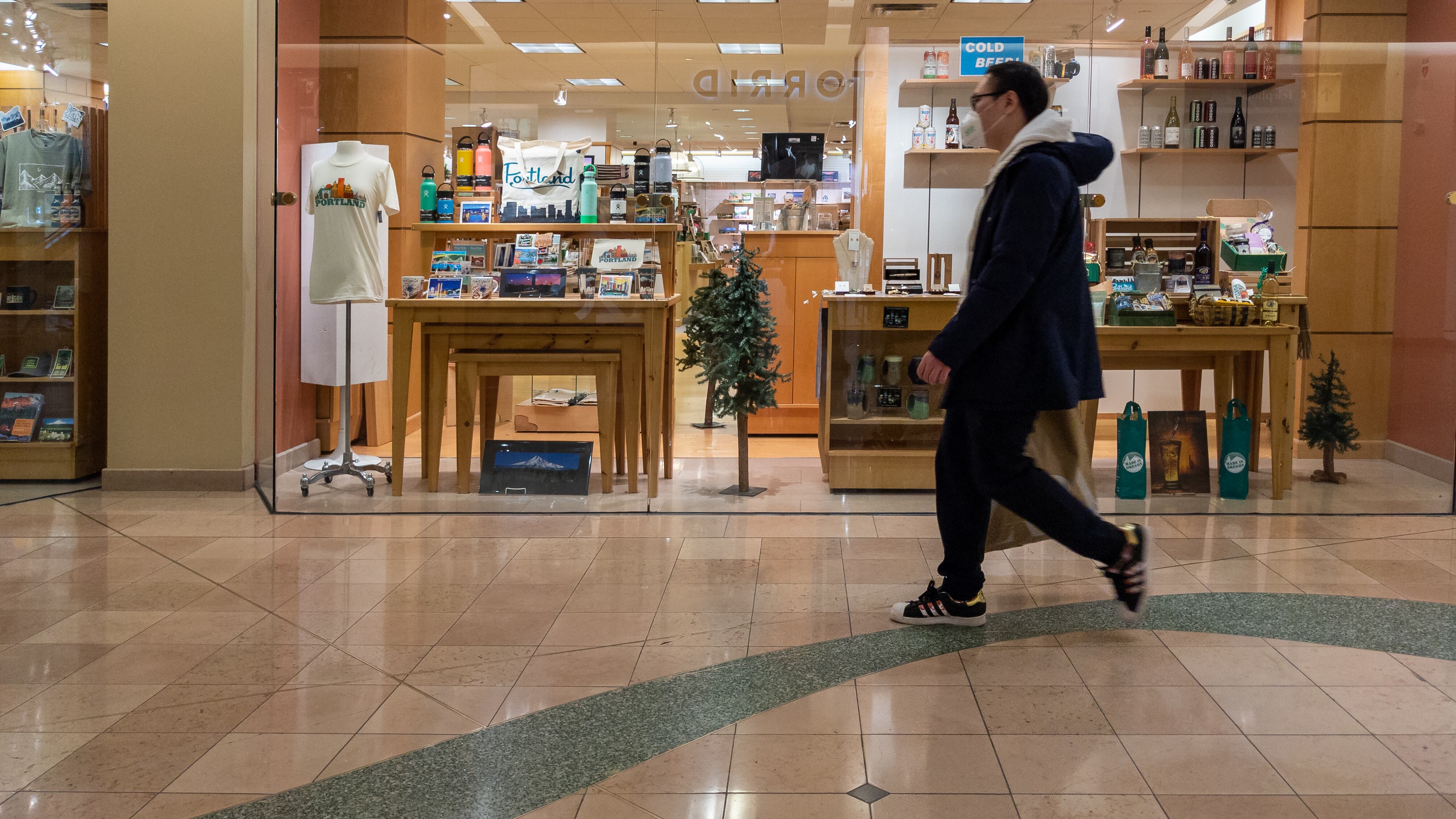 Shopper in mask passes window display in a mall.