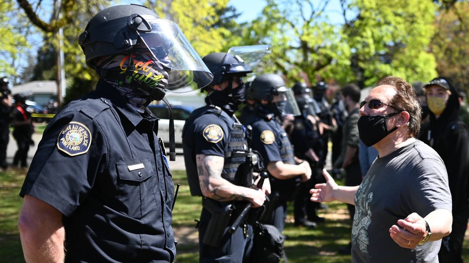 Police guard the scene of a shooting in Lents Park as a man appeals to them.