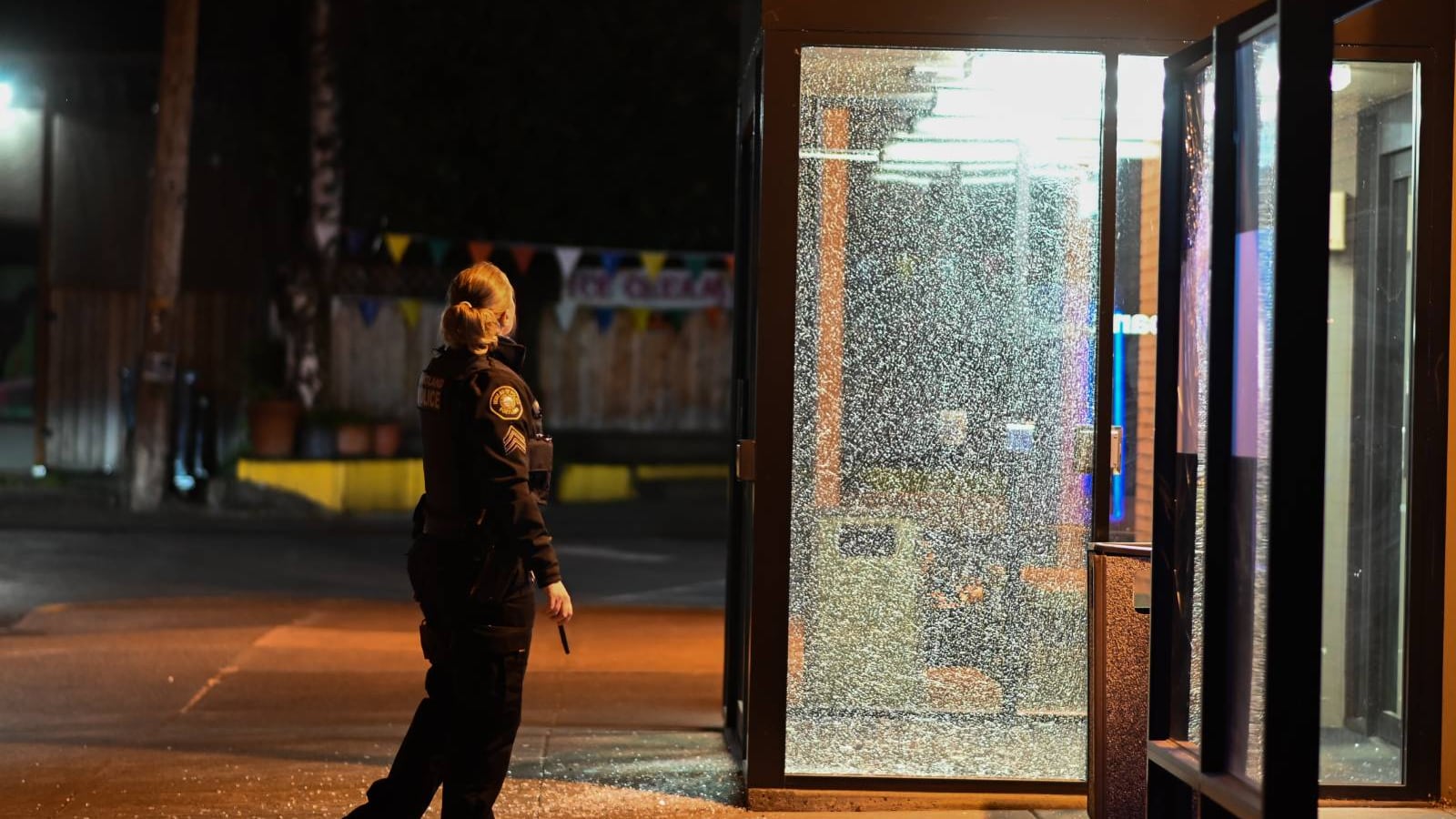 A police officer stares at shattered glass.